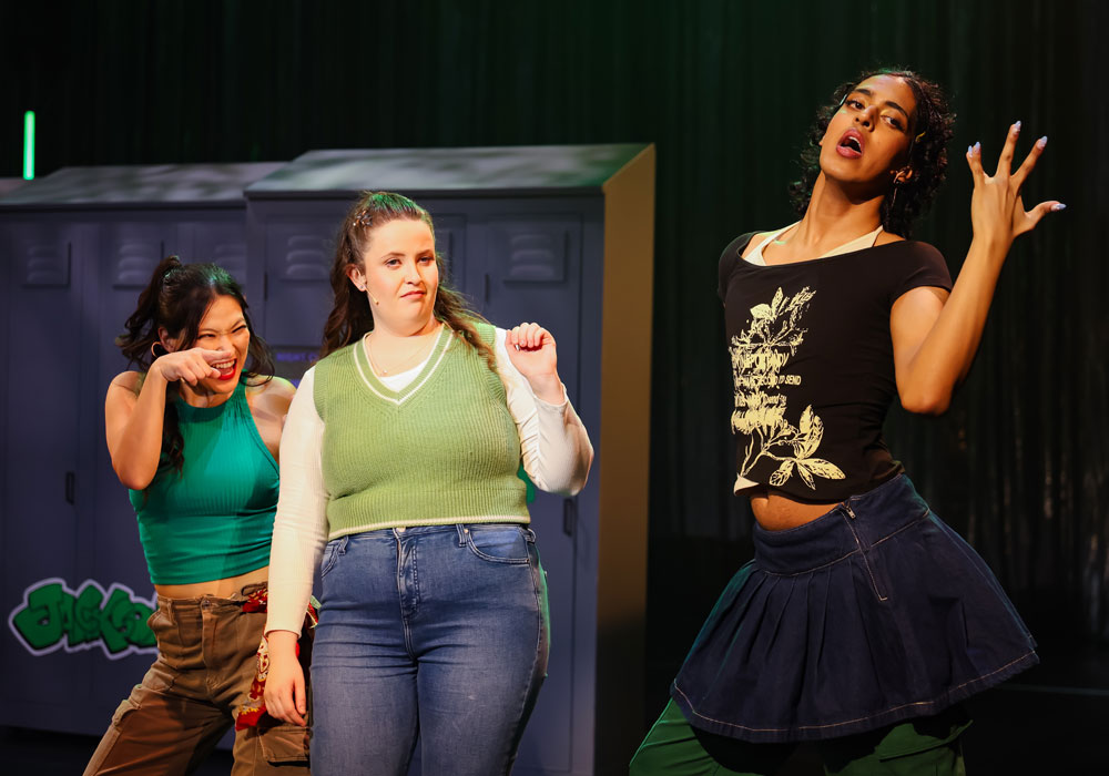 Three female performers dance in a school hallway set, from Theatrical's 2026 staging of Bring It On.